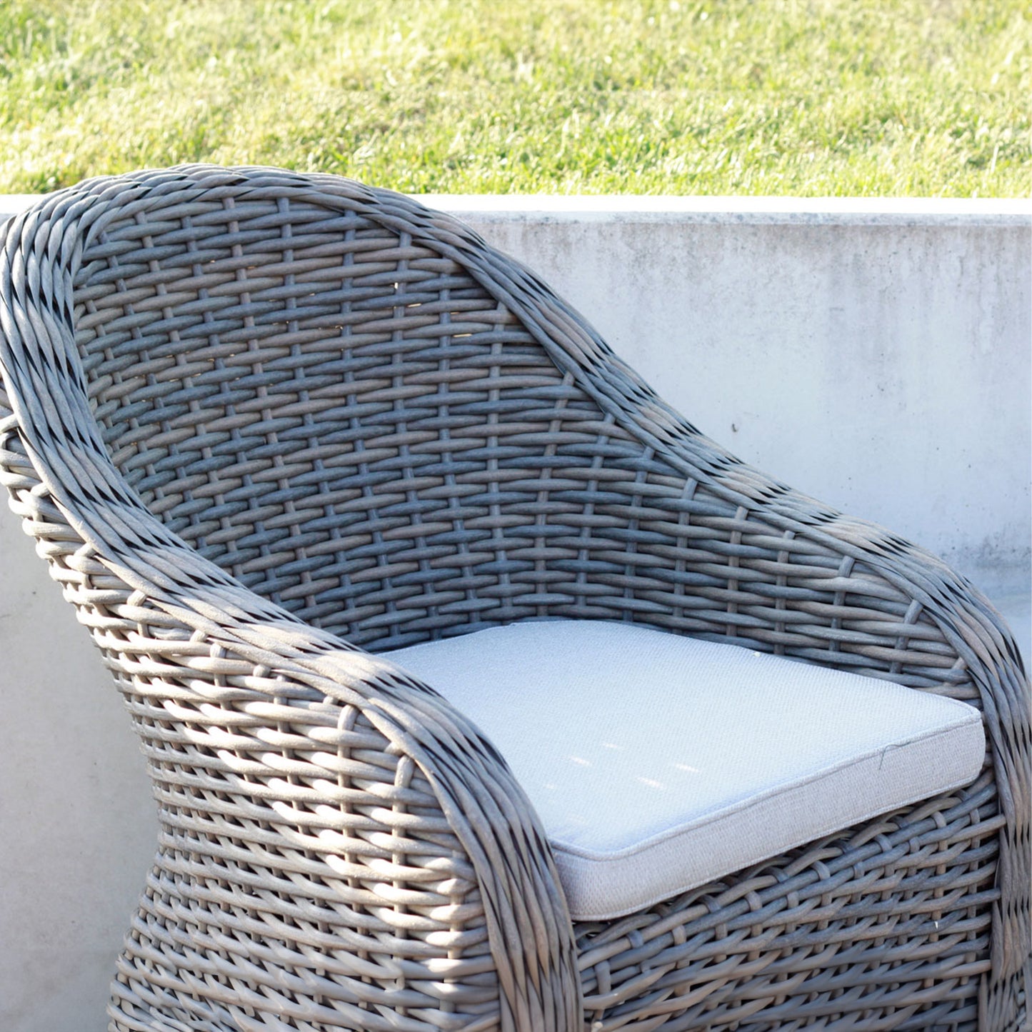 Sitzkissen in beige auf einem Rattanstuhl im Garten
