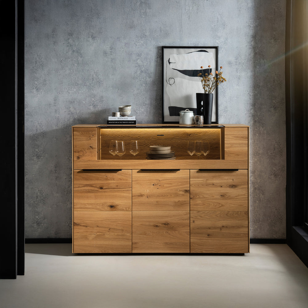 Highboard aus massiver Wildeiche mit Beleuchtungselementen vor einer grauen Wand in Betonoptik