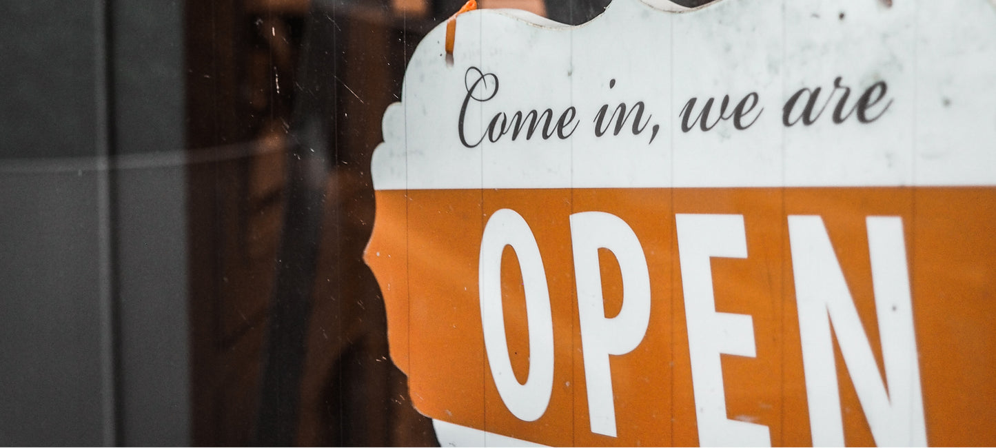 Detailaufnahme von geschnörkeltem weiß und orangefarbenen Come in we are open Schild