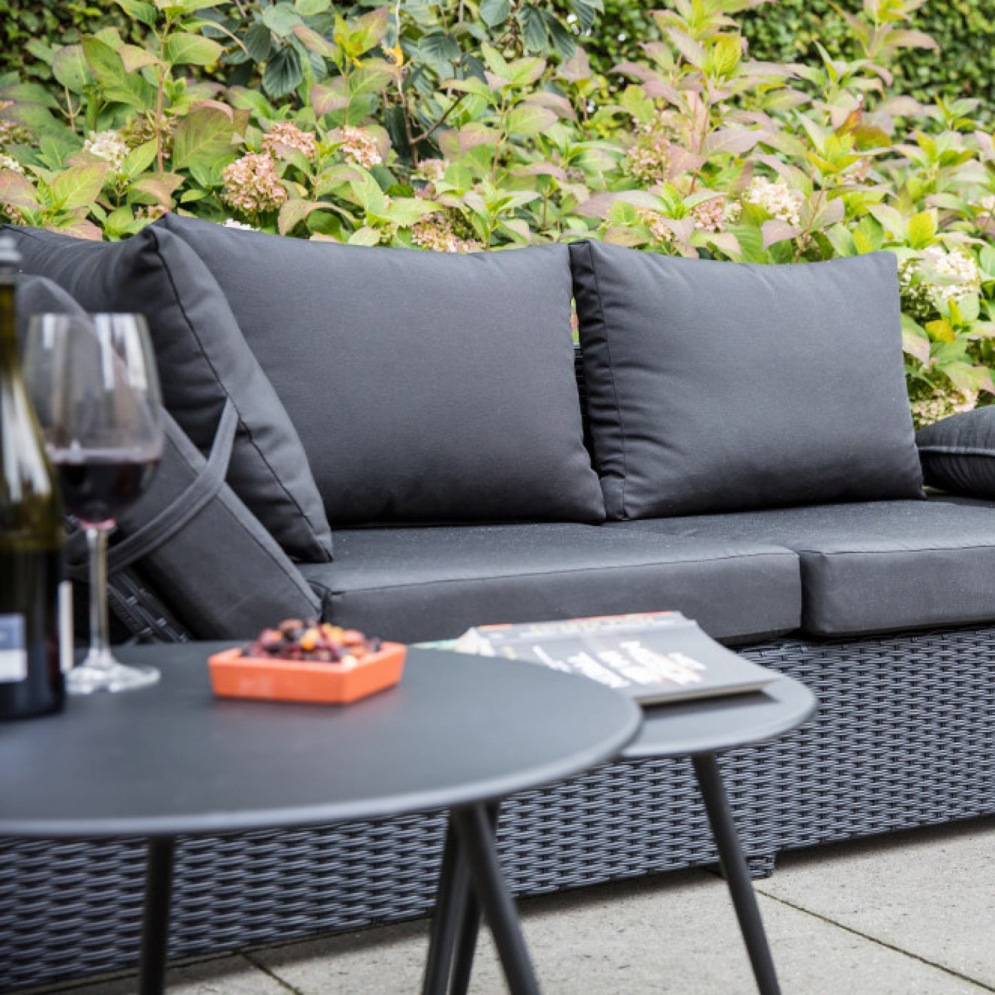 Eiförmiger, stylischer, geflochtener Gartenstuhl mit hellgrauem Sitzpolster und Gartenmöbel von AMD Möbel