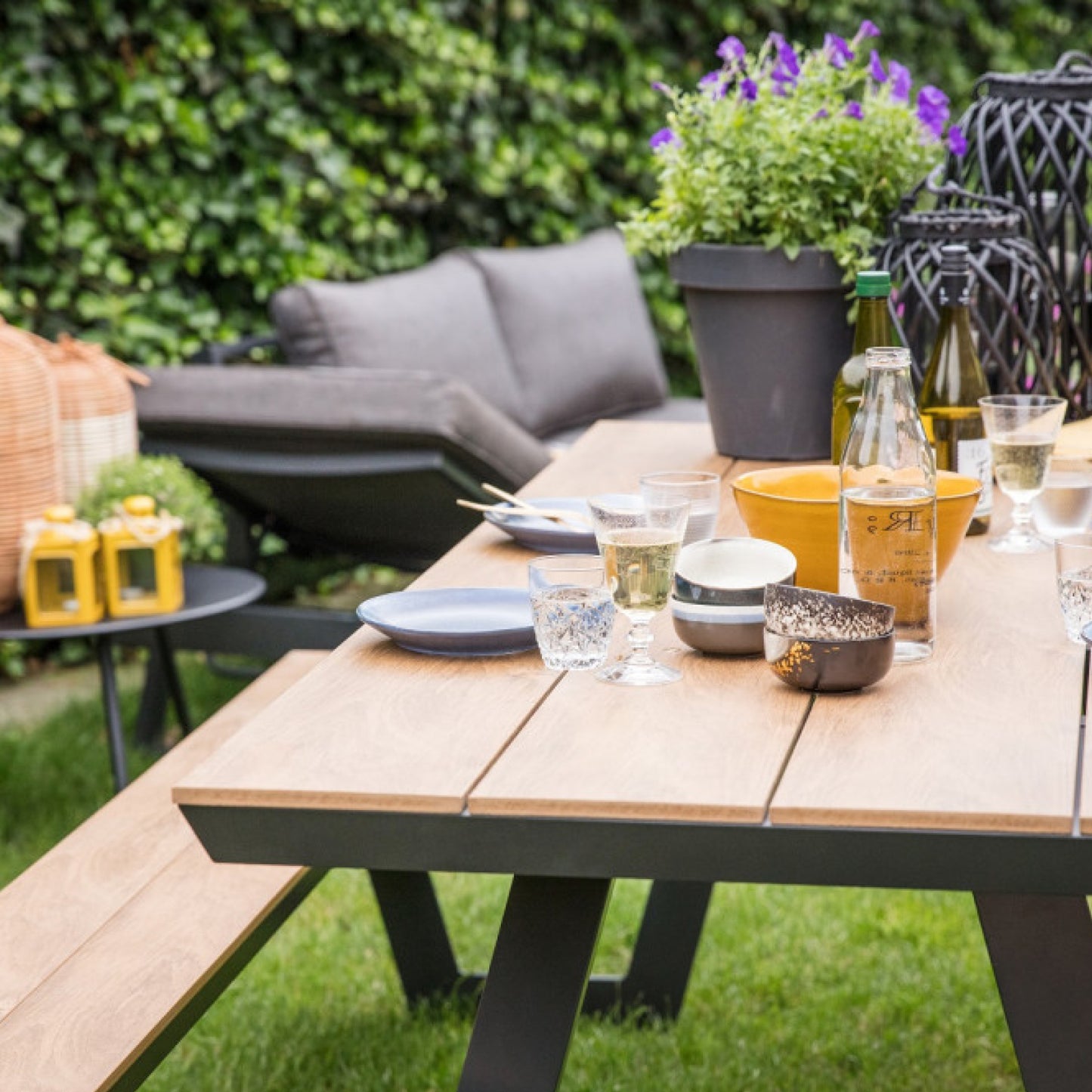 Gedeckter Gartentisch mit integrierten Sitzbänken in modernem Stil